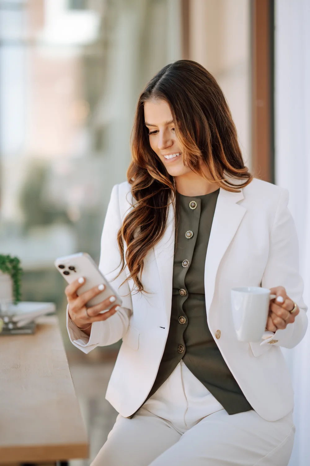 Alexandra Evans looking at her phone while holding a coffee cup